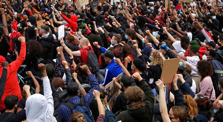 Protesters kneel as they stop briefly in Parliament Square during a demonstration on Wednesday, June 3, 2020, in London, over the death of George Floyd, a black man who died after being restrained by Minneapolis police officers on May 25.
