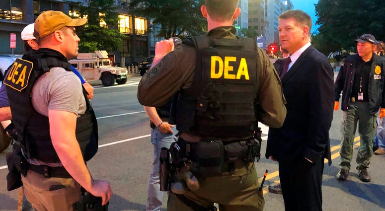 In this Wednesday, June 3, 2020, photo Acting Drug Enforcement Administrator Timothy Shea, right, visits with DEA agents at a checkpoint in Washington.