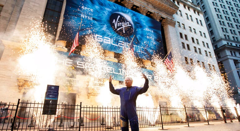 FILE - In this Monday, Oct. 28, 2019 file photo, Sir Richard Branson, founder of Virgin Galactic, poses for a photo outside the New York Stock Exchange as fireworks are exploded before his company's IPO.