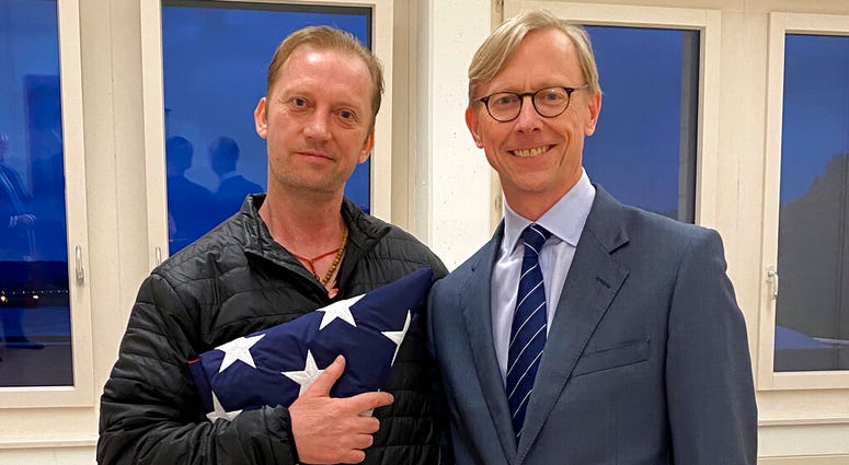 In this image provided by the U.S. State Department, Michael White holds an American flag as he poses for a photo Thursday, June 4, 2020, with U.S.
