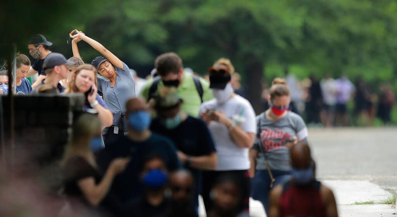 A person stretches as they wait in a line to vote in the Georgia's primary election at Park Tavern on Tuesday, June 9, 2020, in Atlanta.