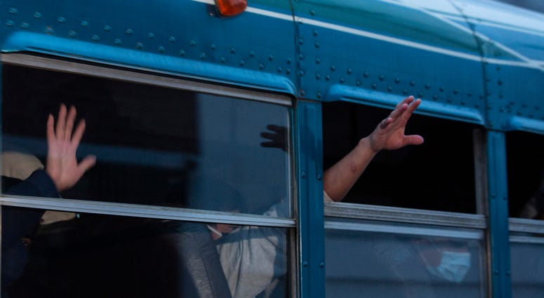 FILE - In this May 4, 2020, file photo, Guatemalans deported from the United States, wave from a bus after arriving at La Aurora airport in Guatemala City.