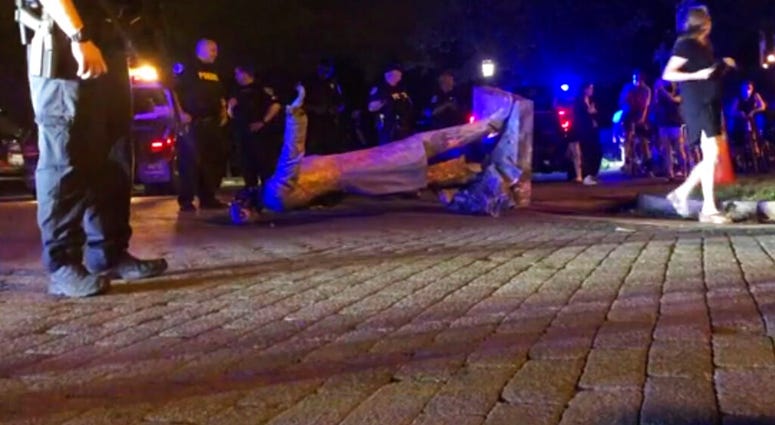 In this image from video, police stand near a toppled statue of Jefferson Davis on Wednesday night, June 10, 2020, in Richmond, Va. Protesters tore down the statue of Confederate President Davis along Monument Avenue.