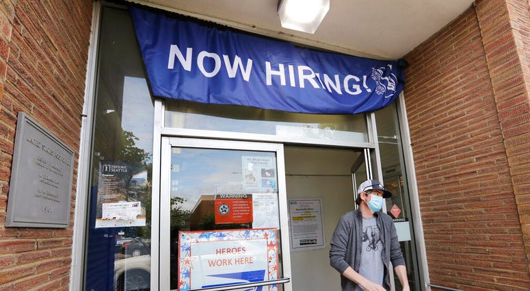 FILE - In this June 4, 2020 photo, a customer walks out of a U.S. Post Office branch and under a banner advertising a job opening, in Seattle.
