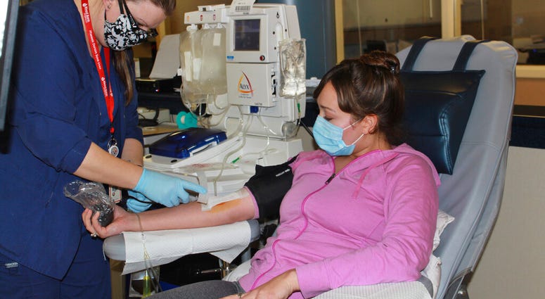 In this April 22, 2020 photo provided by New York Blood Center Enterprises, Aubrie Cresswell, 24, donates convalescent plasma at the Blood Bank of Delmarva Christiana Donor Center in suburban Newark, Del.