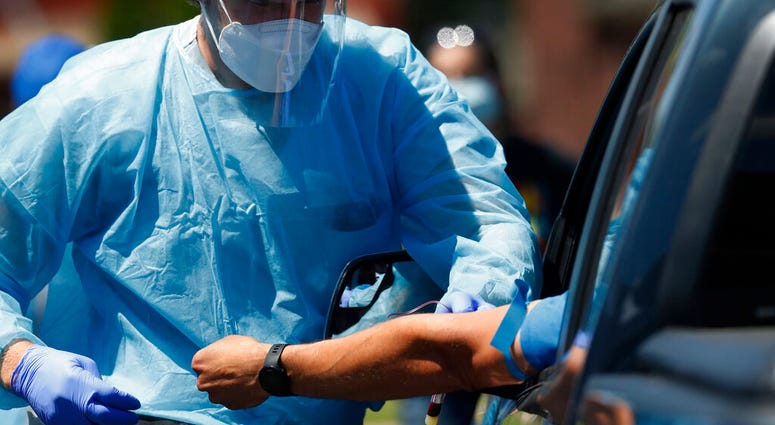 FILE - In this June 12, 2020, file photo, a health worker draws blood for COVID-19 antibody testing in Dearborn, Mich.