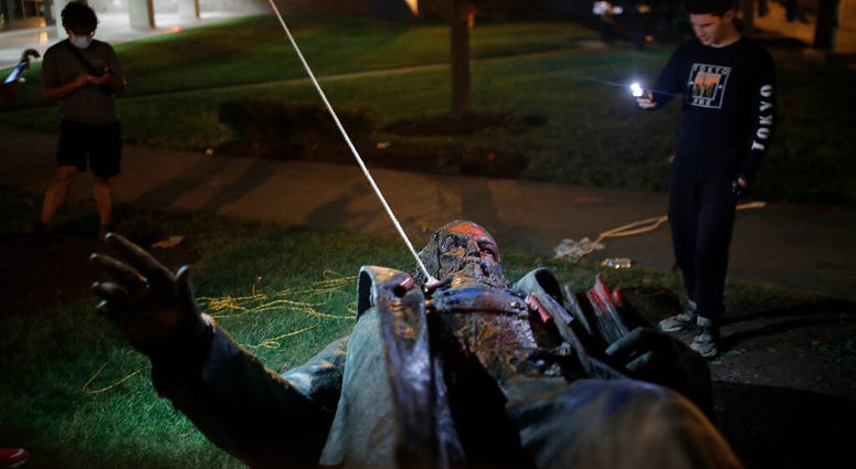 People film the only statue of a Confederate general, Albert Pike, in the nation's capital after it was toppled by protesters and set on fire in Washington early Saturday, June 20, 2020.