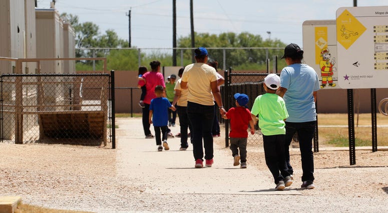FILE - In this Aug. 23, 2019 file photo, immigrants seeking asylum hold hands as they leave a cafeteria at the ICE South Texas Family Residential Center in Dilley, Texas.