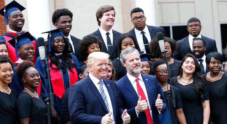 ILE - In this May 13, 2017 file photo, President Donald Trump poses with Liberty University president, Jerry Falwell Jr., center right, in front of a choir during of commencement ceremonies at the school in Lynchburg, Va.