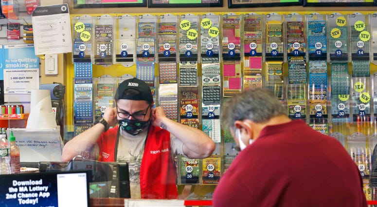 A clerk adjusts his protective mask while waiting on a masked customer at Ted's Stateline Mobil on Wednesday, June 24, 2020 in Methuen, Mass.