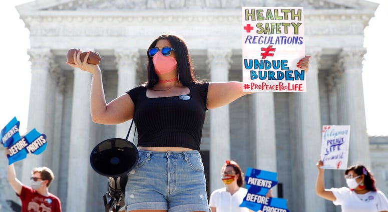 Terrisa Bukovinac, founder of Pro-Life San Francisco, holds a model of a fetus as she and other anti-abortion protesters wait outside the Supreme Court for a decision, Monday, June 29, 2020.
