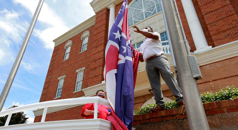 In this Monday, June 29, 2020, City of Tupelo Community Outreach Coordinator Marcus Gary takes down the Mississippi state flag that flew over the City Hall of Tupelo one last time Monday, June 29, 2020. In this Monday, June 29, 2020, City of Tupelo Community Outreach Coordinator Marcus Gary takes down the Mississippi state flag that flew over the City Hall of Tupelo one last time Monday, June 29, 2020.