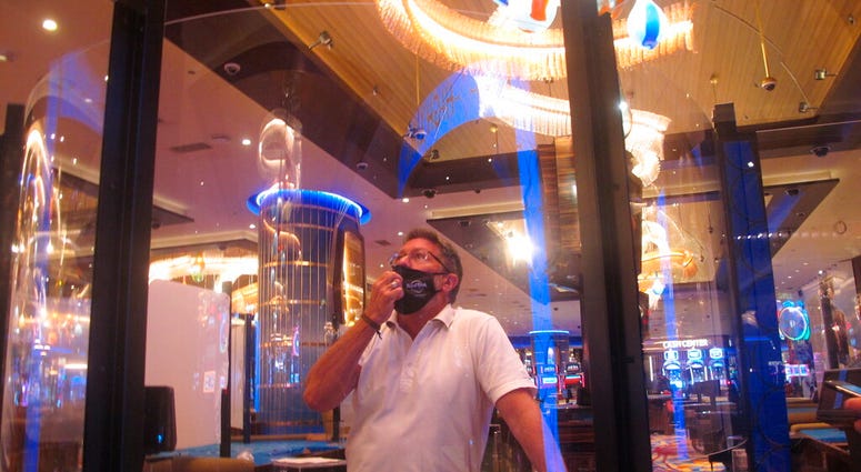 In this June 24, 2020 photo, Joe Lupo, president of the Hard Rock casino in Atlantic City N.J. examines the installation of protective barriers being installed at a card table on the casino floor.