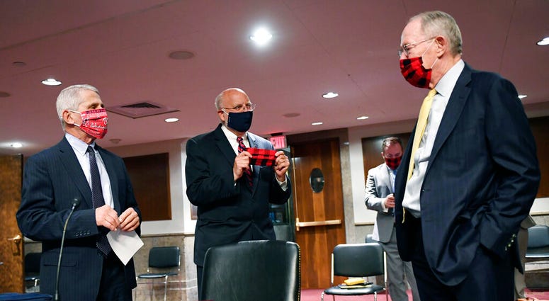 Dr. Anthony Fauci, director of the National Institute for Allergy and Infectious Diseases, left and Center for Disease Control (CDC) Director Dr. Robert Redfield, talk with Sen. Lamar Alexander, R-Tenn., right, as they prepare to testify before a Senate H