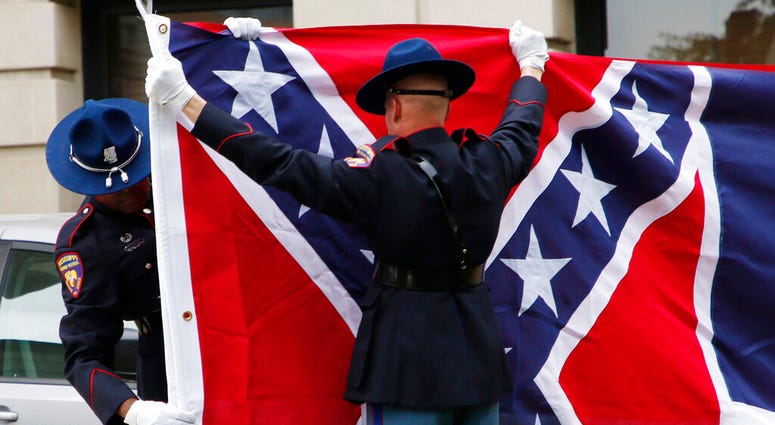A Mississippi Highway Safety Patrol honor guard carefully folds the retired Mississippi state flag after it was raised over the Capitol grounds one final time in Jackson, Miss., Wednesday, July 1, 2020.