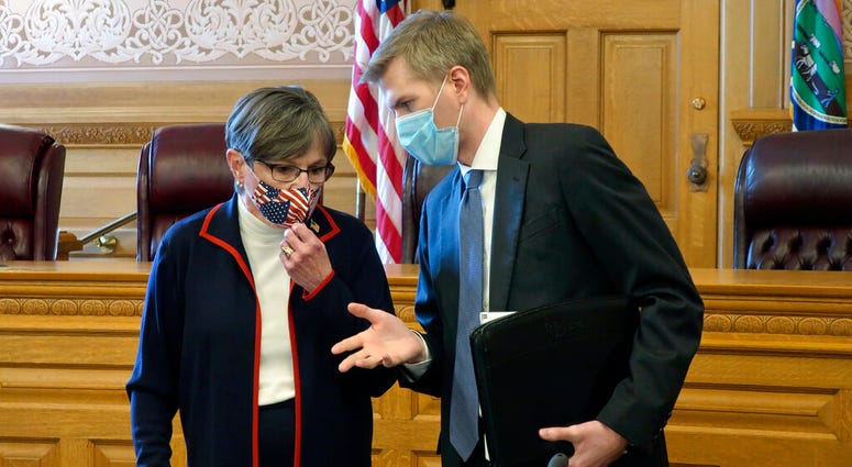 Kansas Gov. Laura Kelly, left, confers with Clay Britton, her chief attorney, before a meeting with legislative leaders about an executive order she issued to require people to wear masks in public, Thursday, July 2, 2020, at the Statehouse in Topeka, Kan
