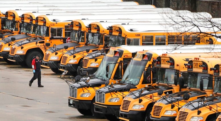 FILE - In this April 27, 2020, file photo, a worker passes public school buses parked at a depot in Manchester, N.H.