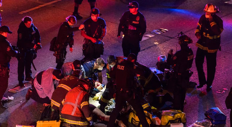 Emergency workers tend to an injured person on the ground after a driver sped through a protest-related closure on the Interstate 5 freeway in Seattle, authorities said early Saturday, July 4, 2020.