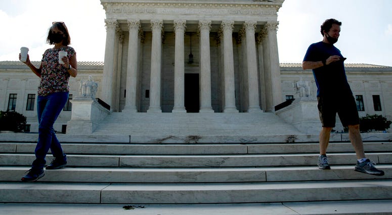 Two people walk down the steps outside the Supreme Court, Thursday, July 9, 2020, in Washington.