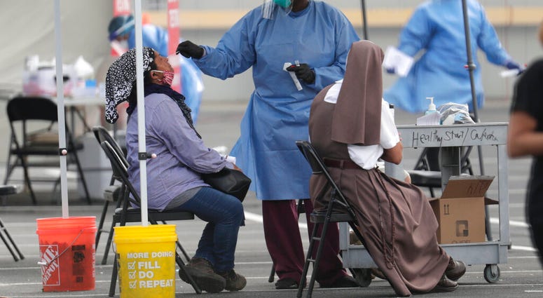 FILE - In this Monday, July 6, 2020 file photo, a health care worker administers a COVID-19 test at a site sponsored by Community Heath of South Florida at the Martin Luther King Jr. Clinica Campesina Health Center in Homestead, Fla.