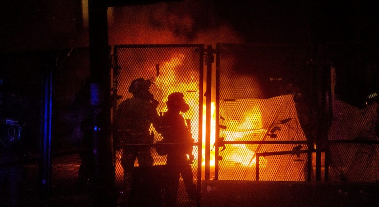 Federal officers guard the U.S. Courthouse as a fire lit by protesters burns on the other side of a perimeter fence in Portland, OreFederal officers guard the U.S. Courthouse as a fire lit by protesters burns on the other side of a perimeter fence in Port