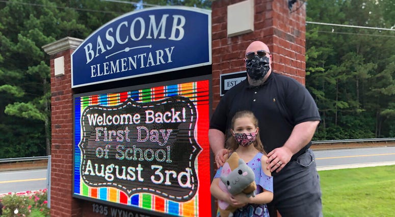 John Barrett and his daughter Autumn pose for photos outside Bascomb Elementary School in Woodstock, Ga., Thursday, July 23, 2020.