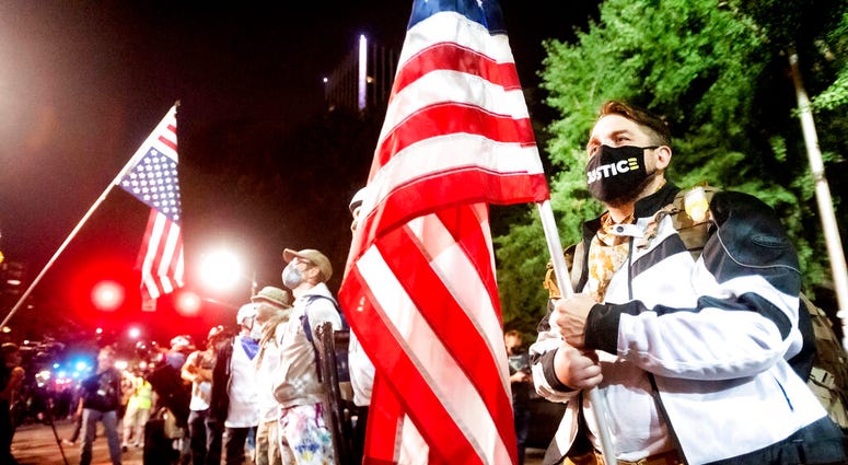 Navy veteran Adam Winther holds a flag while forming a "Wall of Vets" during a Black Lives Matter protest at the Mark O. Hatfield United States Courthouse on Friday, July 31, 2020, in Portland, Ore.