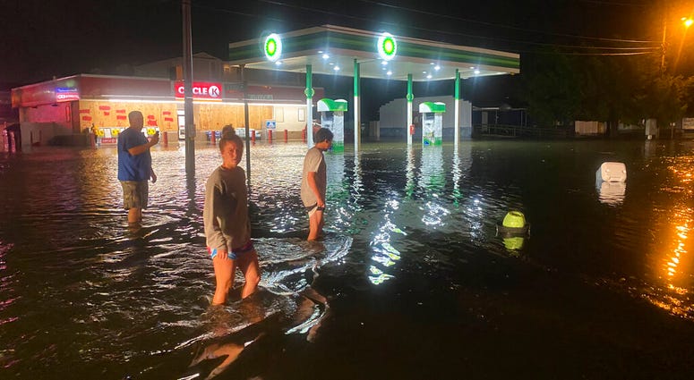 People walk on the flooded Sea Mountain Highway in North Myrtle Beach, S.C., as Isaias neared the Carolinas on Monday night, Aug. 3, 2020.