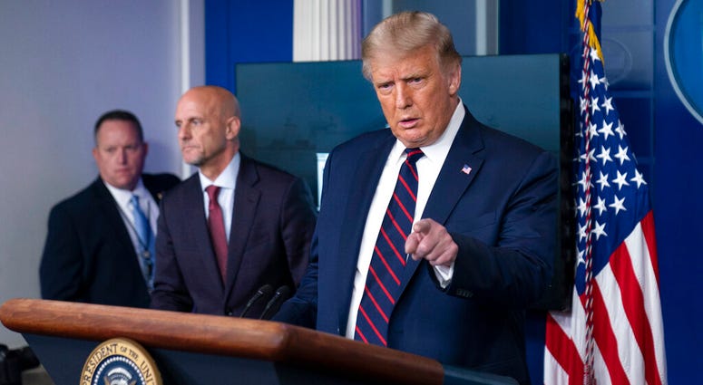 President Donald Trump speaks, accompanied by Food and Drug Administration Commissioner Dr. Stephen Hahn, center, during a media briefing in the James Brady Briefing Room of the White House, Sunday, Aug. 23, 2020, in Washington.