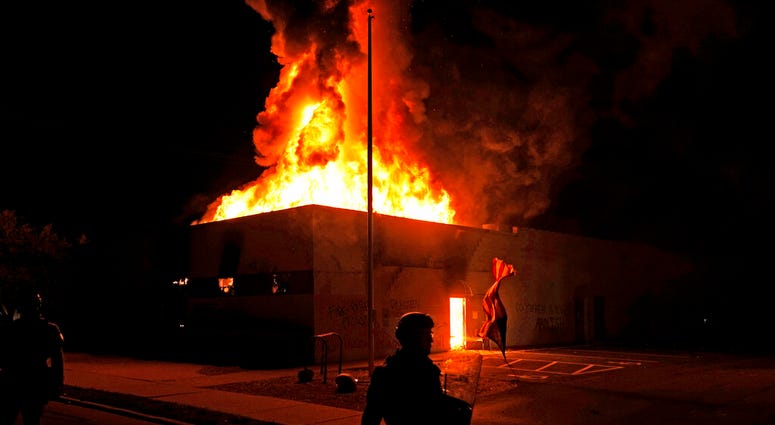 An American flag falls from its pole as police attempt to secure the area after protesters set fire to the department of corrections building, late Monday, Aug. 24, 2020, in Kenosha, Wis. (AP Photo/David Goldman) An American flag falls from its pole as police attempt to secure the area after protesters set fire to the department of corrections building, late Monday, Aug. 24, 2020, in Kenosha, Wis. (AP Photo/David Goldman)