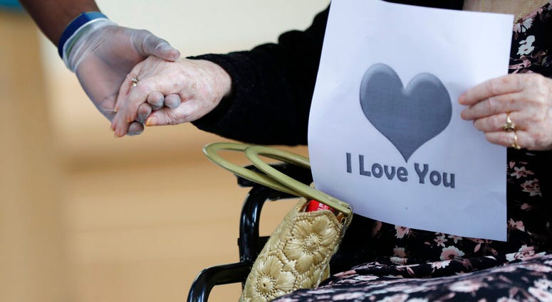 In this July 17, 2020 file photo, a senior citizen holds the hand of a care coordinator at a Health facility in Miami.(AP Photo/Wilfredo Lee) In this July 17, 2020 file photo, a senior citizen holds the hand of a care coordinator at a Health facility in Miami.(AP Photo/Wilfredo Lee)