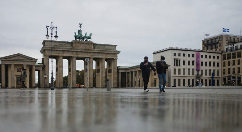 Two men with face maskes cross the desrted Pariser Platz in front of the Brandenburg Gate, a tourist highlight, in Berlin, Germany, Monday, Nov. 2, 2020. (AP Photo/Markus Schreiber) Two men with face maskes cross the desrted Pariser Platz in front of the Brandenburg Gate, a tourist highlight, in Berlin, Germany, Monday, Nov. 2, 2020. (AP Photo/Markus Schreiber)