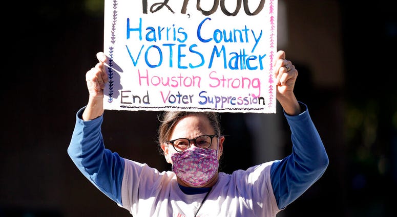 Demonstrator Gina Dusterhoft holds up a sign as she walks to join others standing across the street from the federal courthouse in Houston, Monday, Nov. 2, 2020. (AP Photo/David J. Phillip) Demonstrator Gina Dusterhoft holds up a sign as she walks to join others standing across the street from the federal courthouse in Houston, Monday, Nov. 2, 2020. (AP Photo/David J. Phillip)