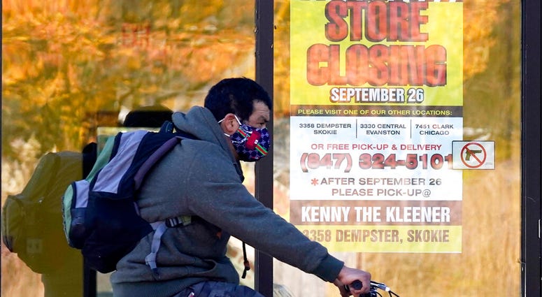 FILE - In this Friday, Nov. 6, 2020, file photo, a man wearing a face mask rides a bicycle past a closed store in Wilmette, Ill. (AP Photo/Nam Y. Huh, File) FILE - In this Friday, Nov. 6, 2020, file photo, a man wearing a face mask rides a bicycle past a closed store in Wilmette, Ill. (AP Photo/Nam Y. Huh, File)