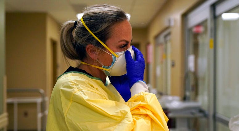 In this Nov. 24, 2020, file photo, registered nurse Chrissie Burkhiser puts on personal protective equipment as she prepares to treat a COVID-19 patient in the emergency room at Scotland County Hospital in Memphis, Mo. (AP Photo/Jeff Roberson, File) In this Nov. 24, 2020, file photo, registered nurse Chrissie Burkhiser puts on personal protective equipment as she prepares to treat a COVID-19 patient in the emergency room at Scotland County Hospital in Memphis, Mo. (AP Photo/Jeff Roberson, File)