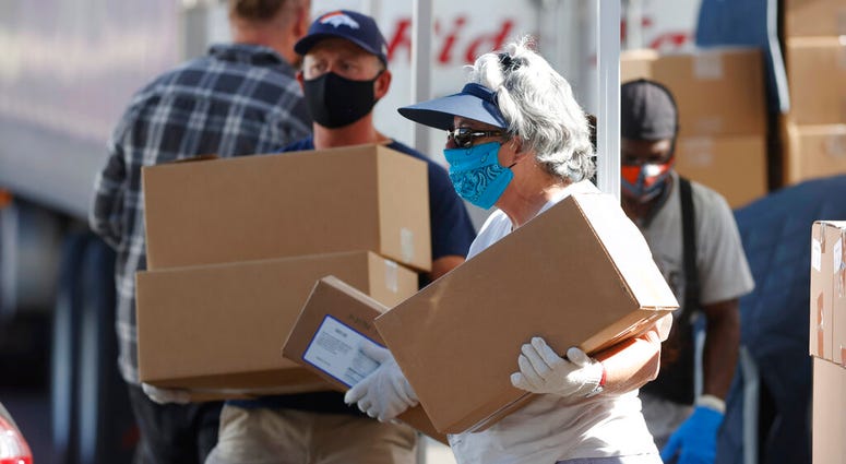 FILE - In this June 26, 2020, file photo, volunteers Juanita MacKenzie, front, and Dave Stutman carry boxes of food to a waiting car at a large mobile pantry set up by the Food Bank of the Rockies. (AP Photo/David Zalubowski, File) FILE - In this June 26, 2020, file photo, volunteers Juanita MacKenzie, front, and Dave Stutman carry boxes of food to a waiting car at a large mobile pantry set up by the Food Bank of the Rockies. (AP Photo/David Zalubowski, File)