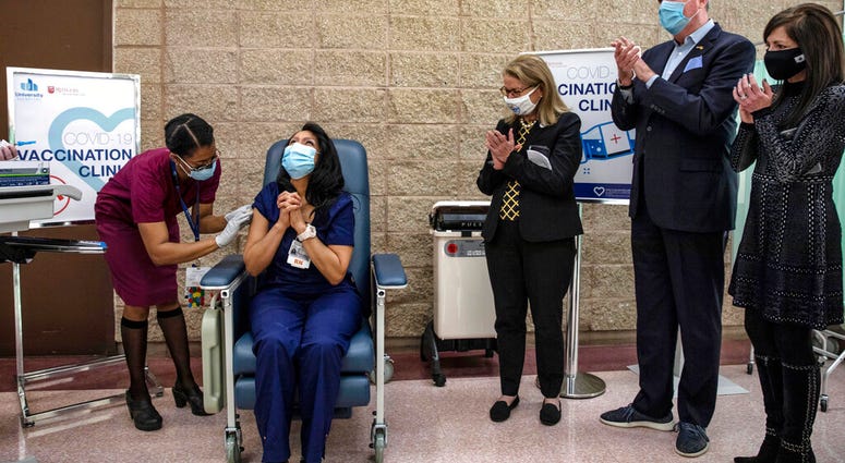 New Jersey Gov. Phil Murphy, second from right, watches as nurse Maritza Beniquez, seated, reacts after receiving the Pfizer-BioNTech COVID-19 vaccine, at University Hospital, in Newark, NJ,