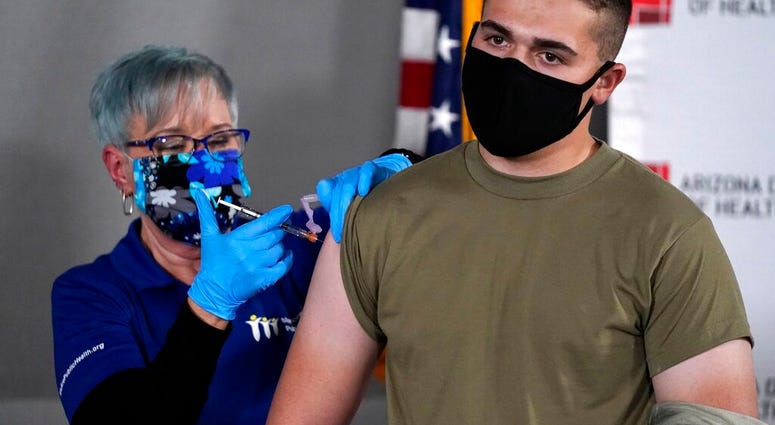 Arizona Air National Guard medic Will Smith, right, receives one of the first doses of the Pfizer-BioNTech vaccine for COVID-19 at the Arizona Department of Health Services State Laboratory from nurse Machrina Leach, Wednesday, Dec. 16, 2020, in Phoenix.