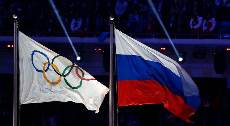 FILE - In this Feb. 23, 2014 file photo the Russian national flag, right, flies after it is hoisted next to the Olympic flag during the closing ceremony of the 2014 Winter Olympics in Sochi, Russia.