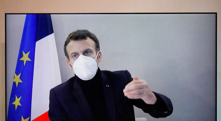 French President Emmanuel Macron is seen on a screen as he attends by video conference a round table for the National Humanitarian Conference (NHC), taken at the Foreign Ministry in Paris
