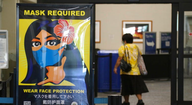 FILE - In this Oct. 2, 2020 file photo, a woman walks into the international airport in Honolulu amid a quarantine rule that effectively shut down the tourism industry in the state.