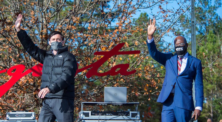 Jon Ossoff, left, and Raphael Warnock wave to the crowd during a campaign rally in Augusta, Ga., Monday, Jan. 4, 2021.