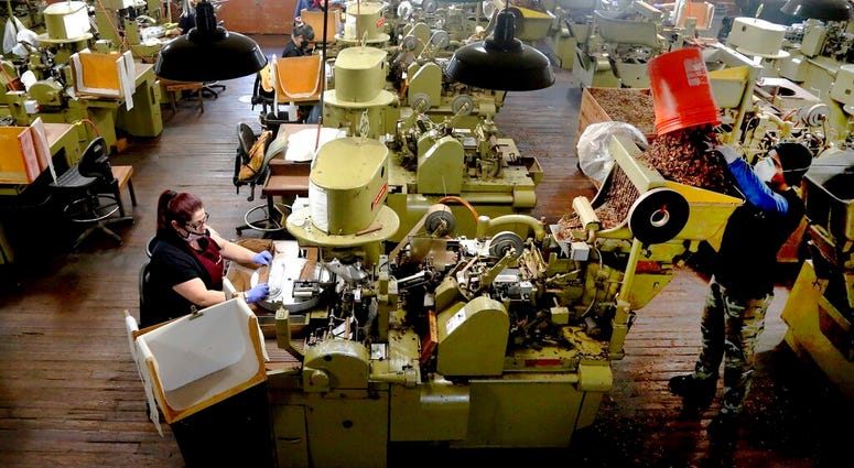 FILE - In this Dec. 14, 2020 file photo, Zeida Hernandez, of Tampa, Fla., left, makes Factory Throwout cigars using an antique hand-operated cigar machine at the J.C. Newman Cigar Co., Tampa's last cigar factory, in Fla.