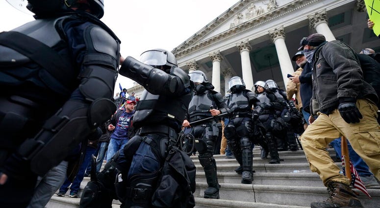 Police in riot gear walk out of the Capitol, Wednesday, Jan. 6, 2021, in Washington.