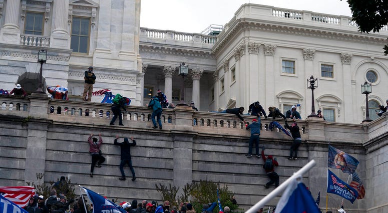 Supporters of President Donald Trump climb the West wall of the the U.S. Capitol on Wednesday, Jan. 6, 2021, in Washington.