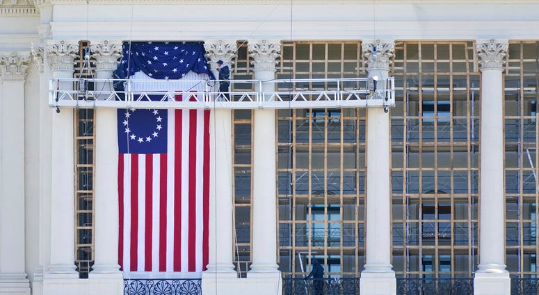 Workers install a flag on the West Front of the U.S. Capitol as preparations take place for President-elect Joe Biden's inauguration, Saturday, Jan. 9, 2021, in Washington.