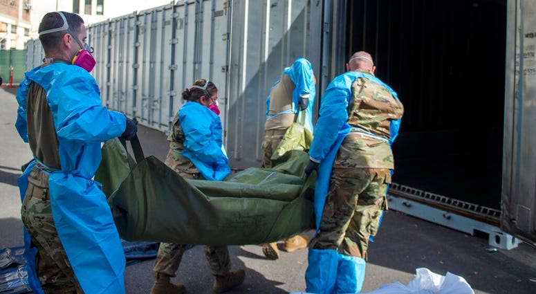 In this Jan. 12, 2021 photo provided by the Los Angeles County Department of Medical Examiner-Coroner, National Guard members assisting with processing COVID-19 deaths, placing them into temporary storage at the medical examiner-coroner's office in L.A. In this Jan. 12, 2021 photo provided by the Los Angeles County Department of Medical Examiner-Coroner, National Guard members assisting with processing COVID-19 deaths, placing them into temporary storage at the medical examiner-coroner's office in L.A.