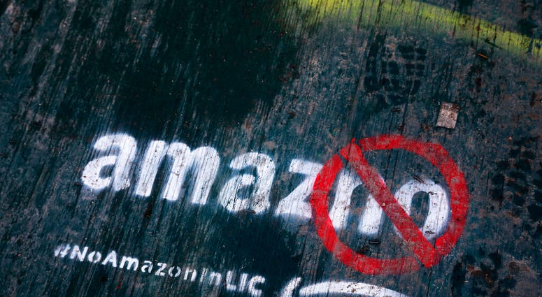 FILE- In this Nov. 16, 2018, file photo graffiti has been painted on a sidewalk by someone opposed to the location of an Amazon headquarters in the Long Island City neighborhood in the Queens borough of New York. Amazon said Thursday, Feb. 14, 2019, that