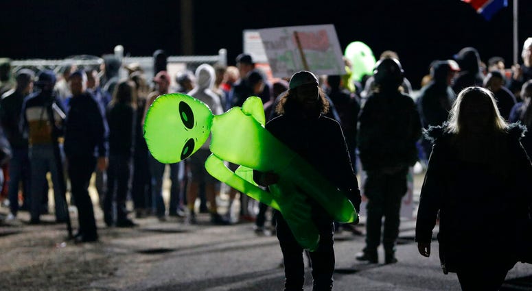 A mans holds an inflatable alien at an entrance to the Nevada Test and Training Range near Area 51 Friday, Sept. 20, 2019, near Rachel, Nev. People gathered at the gate inspired by the "Storm Area 51" internet hoax. (AP Photo/John Locher)