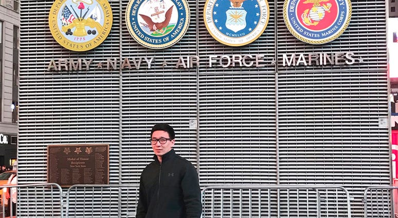 This November 2017 photo provided by Badamsereejid Gansukh shows him in front of a U.S. military recruiting office in New York's Times Square. Gansukh, whose recruiter told him his Turkish language skills would be an asset to the military, said he didn’t